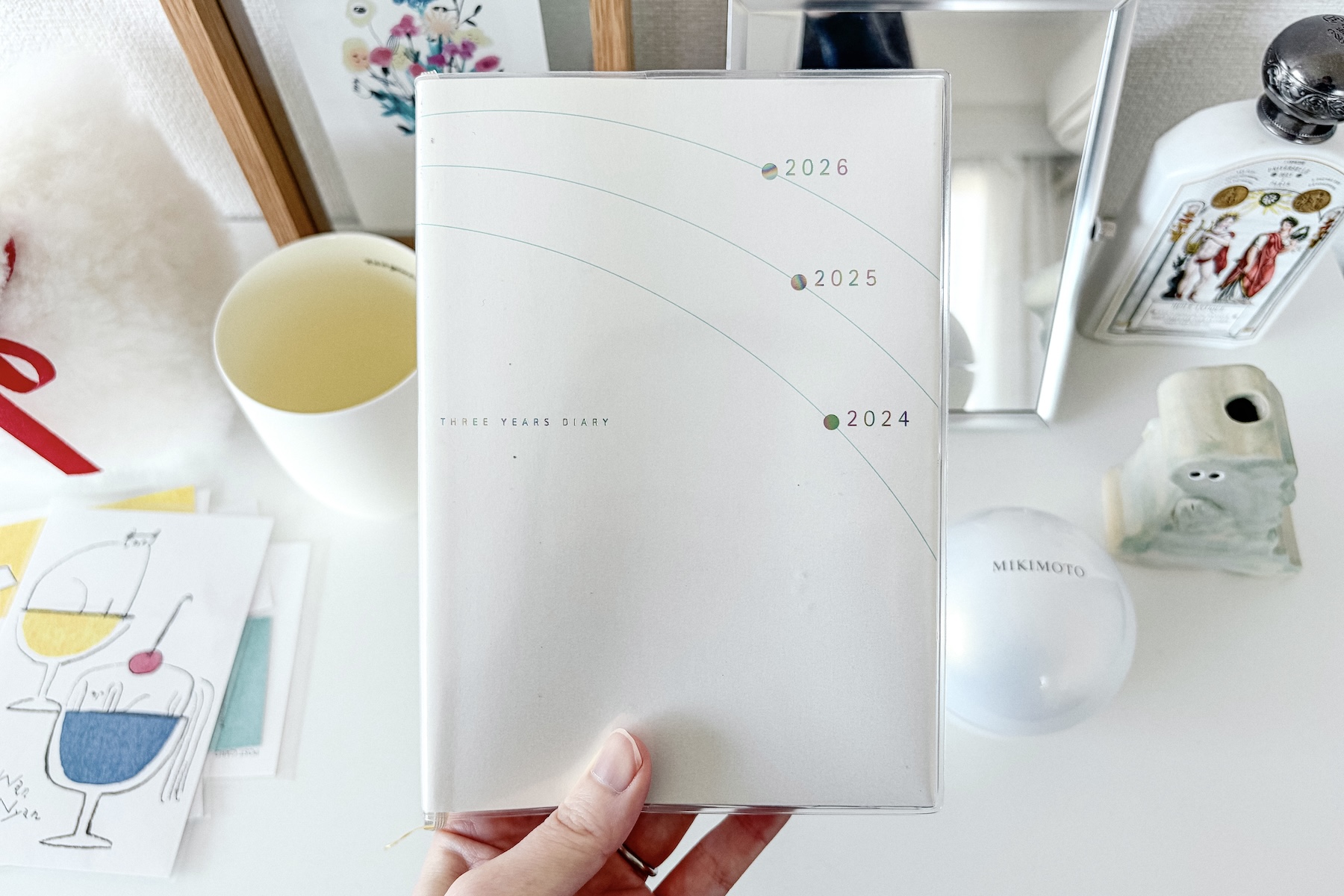 高橋書店の3年日記を手に持っている写真。3年分の年が描かれた表紙とテーブルの小物