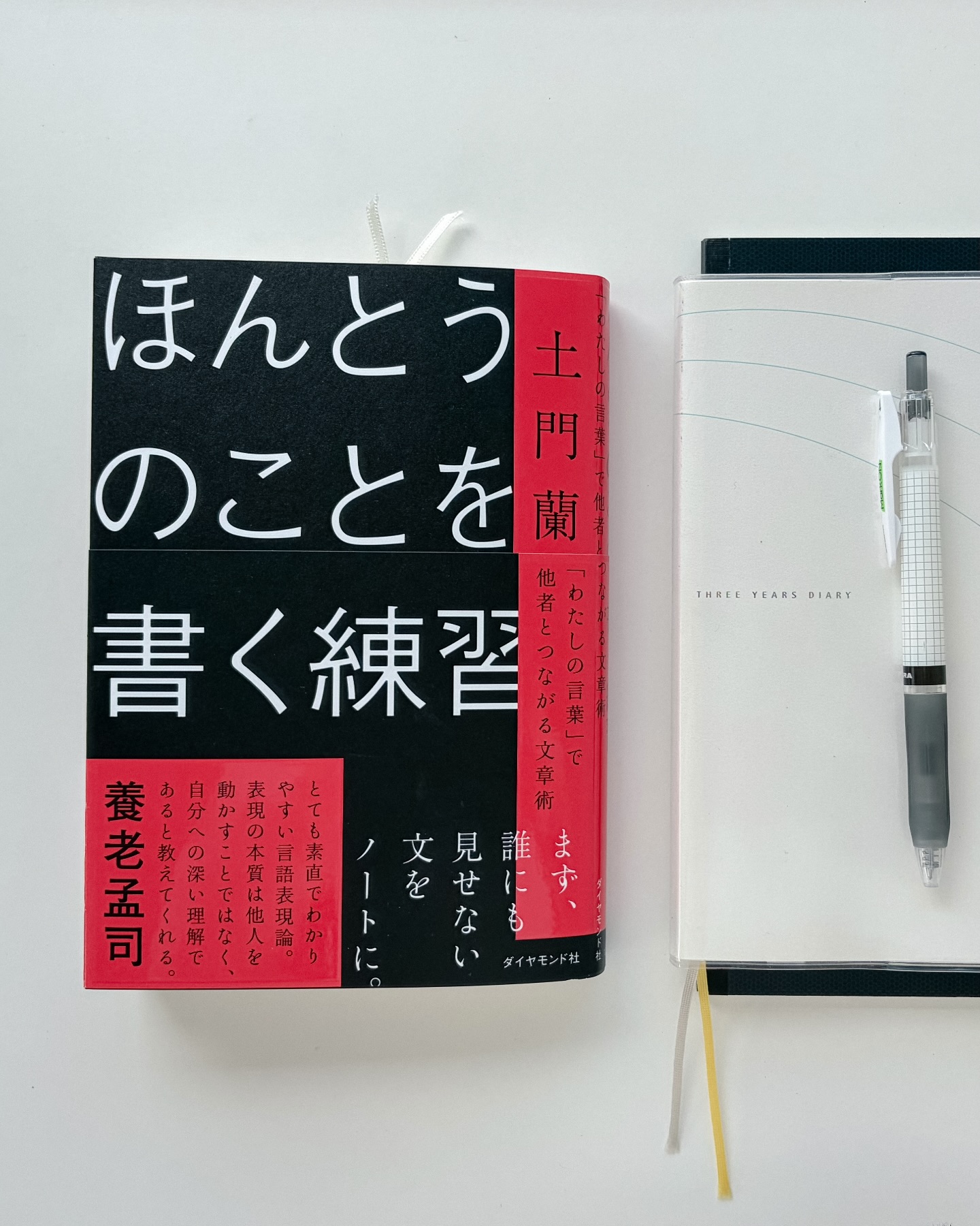 デスクの上に書籍『ほんとうのことを書く練習』と日記帳、ペンが置かれた写真。